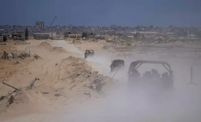 Israeli army vehicles transport a group of soldiers and journalists inside the southern Gaza Strip, Wednesday, July 3, 2024. The Israeli military invited reporters for a tour of Rafah, where the military has been operating since May 6. (AP Photo/Ohad Zwigenberg, Pool)