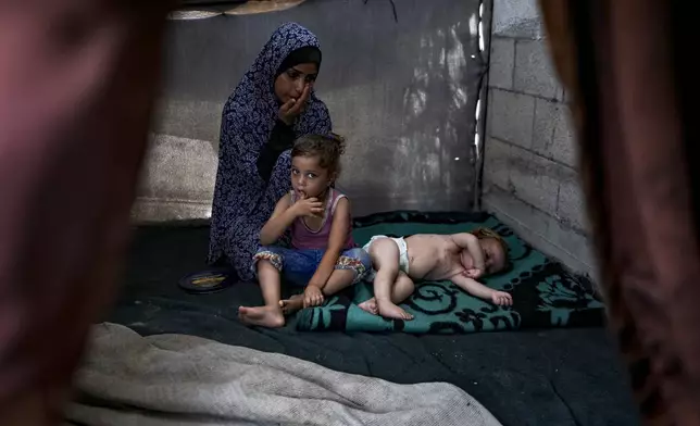 Palestinian Manar al-Hessi, who was displaced by the Israeli bombardment of the Gaza Strip, sits next to her children, at a makeshift tent camp in Deir al-Balah, central Gaza Strip, Monday, July 29, 2024. Skin diseases are running rampant in Gaza, health officials say, from appalling conditions in overcrowded tent camps housing hundreds of thousands of Palestinians driven from their homes. (AP Photo/Abdel Kareem Hana )