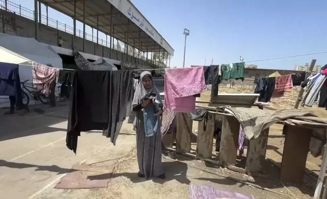 This image from video shows a woman drying clothes, Friday, July 5, 2024 in Gaza City, Gaza Strip. Yarmouk Sports Stadium, once Gaza's biggest soccer arena, is now sheltering thousands of displaced Palestinians who are scraping by with little food or water. (AP Photo)