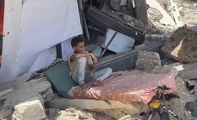 This image from video shows a boy sitting amongst rubble in Yarmouk Sports Stadium Friday, July 5, 2024 in Gaza City, Gaza Strip. Yarmouk Sports Stadium, once Gaza's biggest soccer arena, is now sheltering thousands of displaced Palestinians who are scraping by with little food or water. (AP Photo)