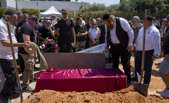 Family and friends of Yevgeny Ferde gather around his grave during his funeral at a cemetery in Rishon Lezion, Israel, on Sunday, July 21, 2024. Yevgeny Ferde was killed in central Tel Aviv by an explosive drone launched by the Yemeni Houthi militant group. (AP Photo/Ohad Zwigenberg)