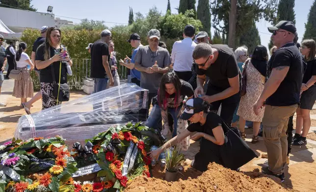 Family and friends of Yevgeny Ferde gather around his grave during his funeral at a cemetery in Rishon Lezion, Israel, on Sunday, July 21, 2024. Ferde, 50, was killed in central Tel Aviv by an explosive drone launched by the Houthi militant group in Yemen on Friday, July 19, 2024. (AP Photo/Ohad Zwigenberg)