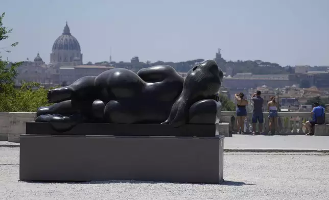 Fernando Botero's "Lying Woman" sculpture is seen in Rome's Pincio Terrace, Friday, July 19, 2024. Rome's storied streets and piazzas have become a vibrant canvas for Botero's exuberant sculptures, turning the city into an open-air museum of voluminous forms and daring artistry. In the background there's St. Peter's Basilica. (AP Photo/Gregorio Borgia)