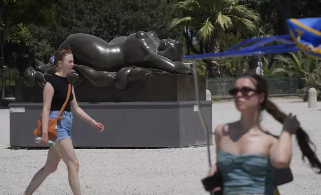 Tourists walk past Fernando Botero's "Sleeping Venus" sculpture at Rome's Pincio Terrace, Friday, July 19, 2024. Rome's storied streets and piazzas have become a vibrant canvas for Botero's exuberant sculptures, turning the city into an open-air museum of voluminous forms and daring artistry. (AP Photo/Gregorio Borgia)