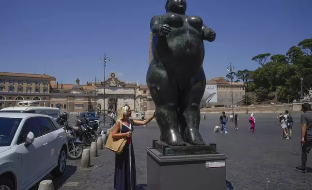 A woman touches Fernando Botero's "Eve" sculpture in Rome's Piazza Del Popolo Square, Friday, July 19, 2024. Rome's storied streets and piazzas have become a vibrant canvas for Botero's exuberant sculptures, turning the city into an open-air museum of voluminous forms and daring artistry. (AP Photo/Gregorio Borgia)