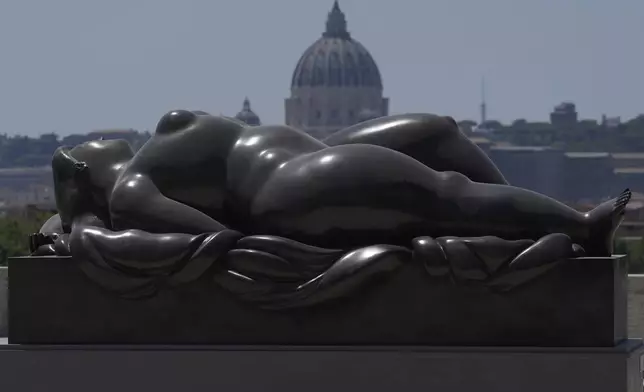 Botero's "Sleeping Venus" sculpture, installed in Rome's Pincio Terrace, Friday, July 19, 2024, appears to be in front of St. Peter's Basilica at The Vatican. Rome's storied streets and piazzas have become a vibrant canvas for Fernando Botero's exuberant sculptures, turning the city into an open-air museum of voluminous forms and daring artistry. (AP Photo/Gregorio Borgia)