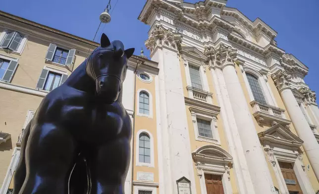 Fernando Botero's "Horse with Bridle" sculpture sits before the Saints Ambrogio and Carlo Basilica at Rome's Via del Corso on Saturday, July 20, 2024. Rome's storied streets and piazzas have become a vibrant canvas for Botero's exuberant sculptures, turning the city into an open-air museum of voluminous forms and daring artistry. (AP Photo/Gregorio Borgia)