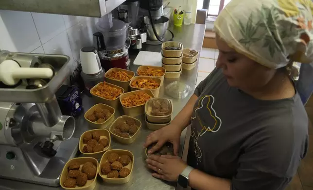 Ruqaia Agha, a Palestinian woman from Ramla, prepares boxes of falafel in the HummusTown kitchen in Rome, Saturday, July 27, 2024. A pair of Syrians have created community that provides support to migrants and vulnerable people in Rome, by sharing the flavors of a homeland torn by civil war. Created in 2018 as a "humanitarian catering service," HummusTown originally aimed at raising funds for families and friends in Syria. (AP Photo/Gregorio Borgia)