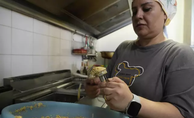 Ruqaia Agha, a Palestinian woman from Ramla, prepares falafel in the HummusTown kitchen in Rome, Saturday, July 27, 2024. A pair of Syrians have created community that provides support to migrants and vulnerable people in Rome, by sharing the flavors of a homeland torn by civil war. Created in 2018 as a "humanitarian catering service," HummusTown originally aimed at raising funds for families and friends in Syria. (AP Photo/Gregorio Borgia)