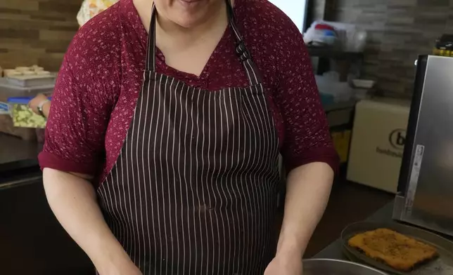 Jumana Farho, from Syria, prepares Kunafa a traditional Syrian cake in the HummusTown kitchen in Rome, Saturday, July 27, 2024. A pair of Syrians have created community that provides support to migrants and vulnerable people in Rome, by sharing the flavors of a homeland torn by civil war. Created in 2018 as a "humanitarian catering service," HummusTown originally aimed at raising funds for families and friends in Syria. (AP Photo/Gregorio Borgia)