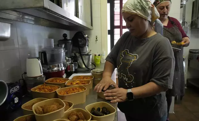 Ruqaia Agha, a Palestinian woman from Ramla, prepares boxes of falafel in the HummusTown kitchen in Rome, Saturday, July 27, 2024. A pair of Syrians have created community that provides support to migrants and vulnerable people in Rome, by sharing the flavors of a homeland torn by civil war. Created in 2018 as a "humanitarian catering service," HummusTown originally aimed at raising funds for families and friends in Syria. (AP Photo/Gregorio Borgia)