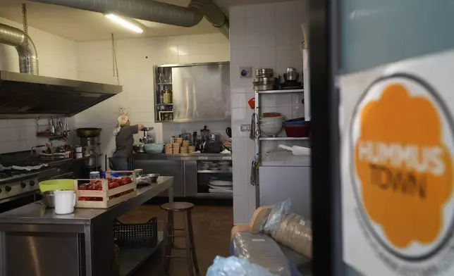 Ruqaia Agha, a Palestinian woman from Ramla, works in the HummusTown kitchen in Rome, Saturday, July 27, 2024. A pair of Syrians have created community that provides support to migrants and vulnerable people in Rome, by sharing the flavors of a homeland torn by civil war. Created in 2018 as a "humanitarian catering service," HummusTown originally aimed at raising funds for families and friends in Syria. (AP Photo/Gregorio Borgia)