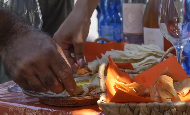 Customers enjoy hummus outside the HummusTown bistro in Rome, Saturday, July 27, 2024. A pair of Syrians have created community that provides support to migrants and vulnerable people in Rome, by sharing the flavors of a homeland torn by civil war. Created in 2018 as a "humanitarian catering service," HummusTown originally aimed at raising funds for families and friends in Syria. (AP Photo/Gregorio Borgia)