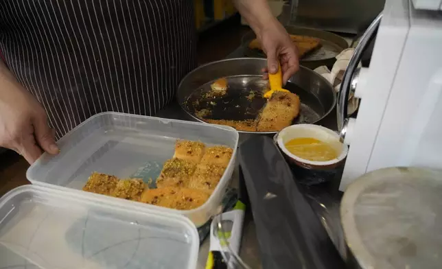 Jumana Farho, from Syria, prepares Kunafa a traditional Syrian cake in the HummusTown kitchen in Rome, Saturday, July 27, 2024. A pair of Syrians have created community that provides support to migrants and vulnerable people in Rome, by sharing the flavors of a homeland torn by civil war. Created in 2018 as a "humanitarian catering service," HummusTown originally aimed at raising funds for families and friends in Syria. (AP Photo/Gregorio Borgia)