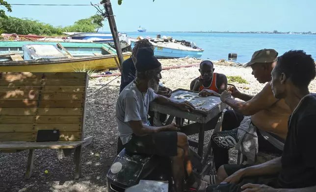 Fishermen play dominoes after pulling their boats out of the water to protect them from Hurricane Beryl in Kingston, Jamaica, Tuesday, July 2, 2024. (AP Photo/Collin Reid)