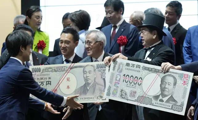 Officials pose with enlarged copies of the new and old 10000 yen banknotes during the "10,000 Yen Bill Handover Ceremony" at Tokyo Stock Exchange Wednesday, July 3, 2024, in Tokyo. New 10000 yen bill featuring a portrait of local figure Shibusawa Eiichi, the "father of Japanese capitalism." From Fukaya City. Nakatsu City is where Yukichi Fukuzawa, a figure of previous 10000 yen bill, was from. (AP Photo/Eugene Hoshiko)