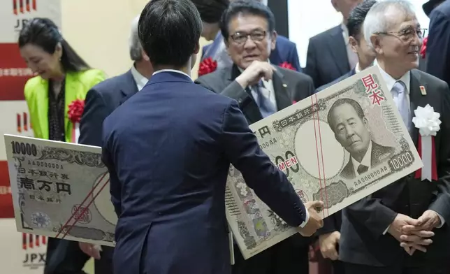 A staff holds an enlarged copies of the new and old 10000 yen banknotes after the "10,000 Yen Bill Handover Ceremony" at Tokyo Stock Exchange Wednesday, July 3, 2024, in Tokyo. Newly designed banknotes, 10,000 yen (about US$61), 5,000 yen (about US$30) and 1,000 yen (about US$6) went into circulation Wednesday for the first time in 20 years. (AP Photo/Eugene Hoshiko)