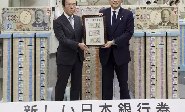 Japanese Prime Minister Fumio Kishida, right, and Bank of Japan Governor Kazuo Ueda hold the country’s new banknotes in a frame, during a ceremony to mark the release of the banknotes, at the BOJ headquarters in Tokyo, Japan, Wednesday, July 3, 2024. The words at bottom read: New Bank of Japan banknotes start being issued. (Japan Pool/Kyodo News via AP)