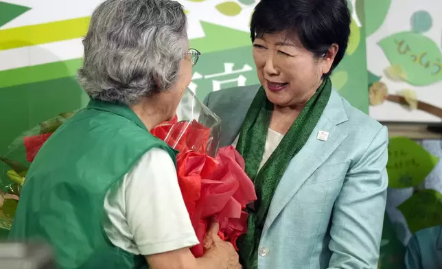 Incumbent Tokyo Gov. Yuriko Koike is handed a bouquet of flowers after she was elected for Tokyo's gubernatorial election in Tokyo, Sunday, July 7, 2024. (AP Photo/Hiro Komae)