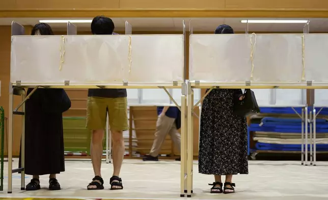 People prepare to cast their votes at a polling place for Tokyo's governor election in Tokyo, Sunday, July 7, 2024. Voters in Tokyo are casting ballots Sunday to decide whether to reelect conservative Yuriko Koike as governor of Japan's influential capital for a third four-year term. (AP Photo/Hiro Komae)