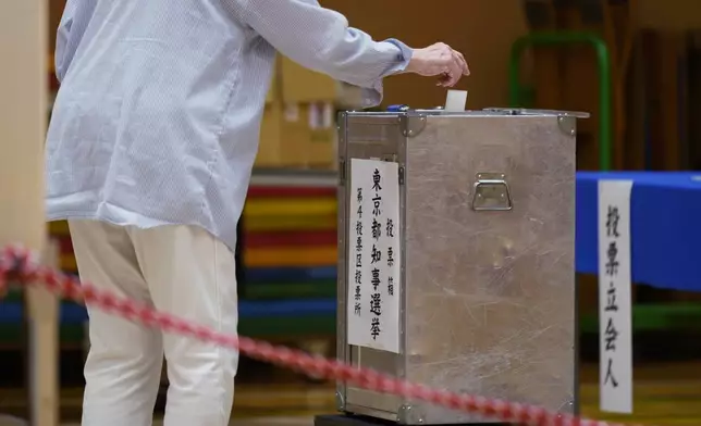 A woman casts her vote at a polling place for Tokyo's governor election in Tokyo, Sunday, July 7, 2024. Voters in Tokyo are casting ballots Sunday to decide whether to reelect conservative Yuriko Koike as governor of Japan's influential capital for a third four-year term. (AP Photo/Hiro Komae)