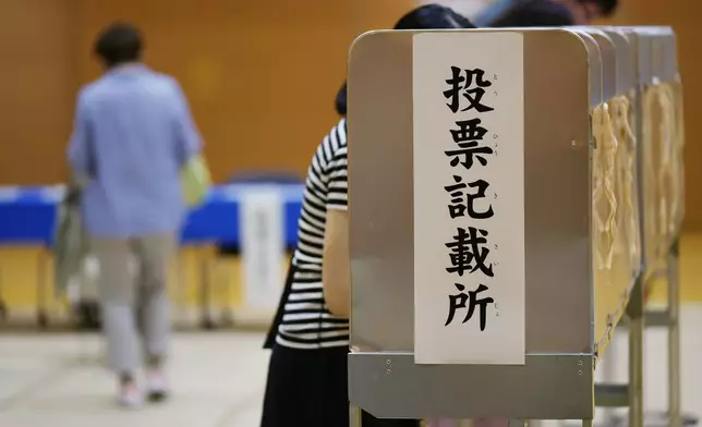 People prepare to cast their vote at a polling place for Tokyo's governor election in Tokyo, Sunday, July 7, 2024. Voters in Tokyo are casting ballots Sunday to decide whether to reelect conservative Yuriko Koike as governor of Japan's influential capital for a third four-year term. (AP Photo/Hiro Komae)