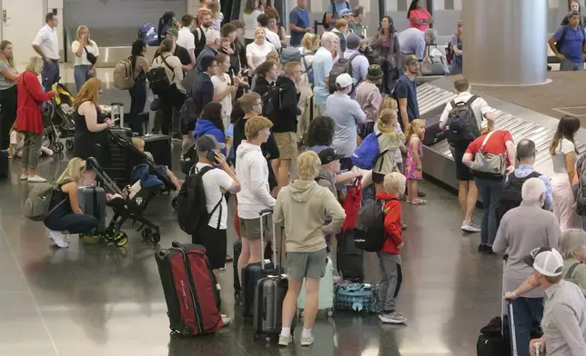 Holiday travelers wait for their luggage after arriving at Salt Lake City International Airport Wednesday, July 3, 2024, in Salt Lake City. (AP Photo/Rick Bowmer)