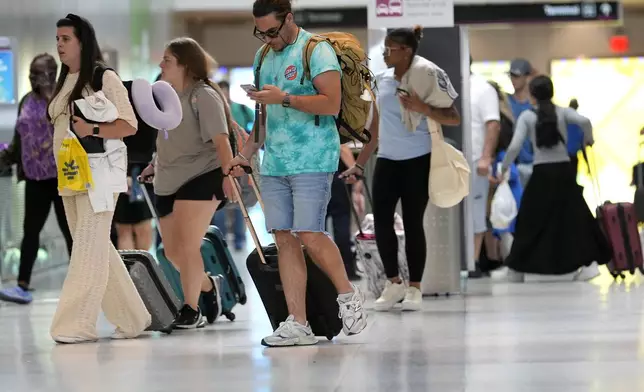 Travelers walk through Miami International Airport, Wednesday, July 3, 2024, in Miami. (AP Photo/Lynne Sladky)