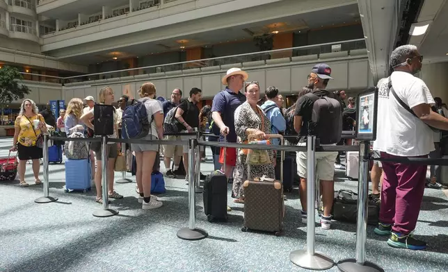 Passengers wait in line to go through TSA security screening at Orlando International Airport Wednesday, July 3, 2024, in Orlando, Fla. (AP Photo/John Raoux)