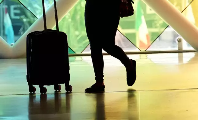 A traveler walks through Miami International Airport, Wednesday, July 3, 2024, in Miami. A long Fourth of July holiday weekend is expected to create new travel records. (AP Photo/Lynne Sladky)