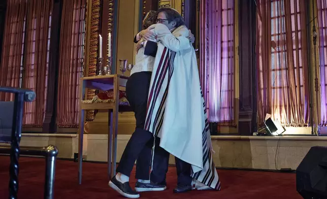Rabbi Sharon Kleinbaum, right, hugs her wife, Randi Weingarten, left, during her last service at the Masonic Hall, Friday, June 28, 2024, in New York. After leading the nation’s largest LGBTQ+ synagogue through the myriad ups and downs of the modern gay-rights movement for the last three decades, she is now stepping down from that role and shifting into retirement. The synagogue that she led for 32 years — Congregation Beit Simchat Torah in midtown Manhattan — will have to grapple with its identity after being defined by its celebrity rabbi for so long. (AP Photo/Andres Kudacki)