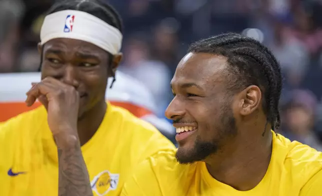 Los Angeles Lakers guard Bronny James, right, laughs with teammates while sitting on the bench during the second half of an NBA summer league basketball game against the Golden State Warriors in San Francisco, Sunday, July 7, 2024. (AP Photo/Nic Coury)