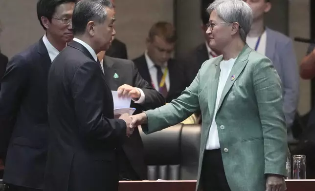 Chinese Foreign Minister Wang Yi, left, shakes hands with Australian Minister of Foreign Affairs Penny Wong, right, during the East Asia Summit Foreign Ministers' Meeting in Vientiane, Laos, Saturday, July 27, 2024. (AP Photo/Achmad Ibrahim, Pool)