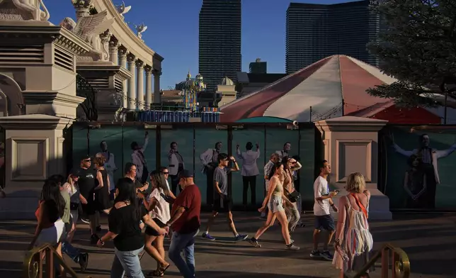 People shield their eyes from the sun along the Las Vegas Strip, Sunday, July 7, 2024, in Las Vegas. The city set an all time record high of 120 F (48.8 C) Sunday as a heat wave spread across the Western U.S. sending many residents in search of a cool haven from the dangerously high temperatures. (AP Photo/John Locher)