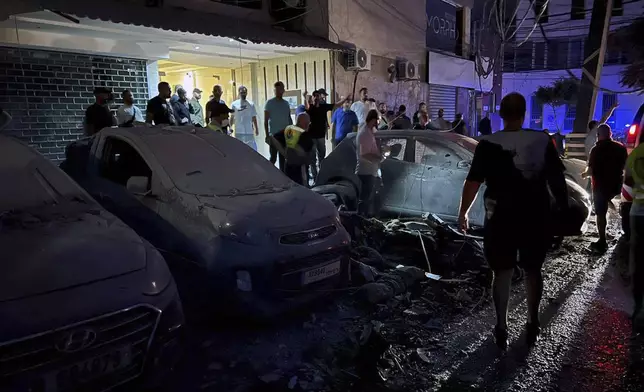 People inspect damaged cars in the southern suburbs of Beirut, Lebanon, Tuesday, July 30, 2024. An Israeli airstrike hit Hezbollah's stronghold south of Beirut Tuesday evening causing damage, a Hezbollah official and the group's TV station said. (AP Photo/Hussein Malla)