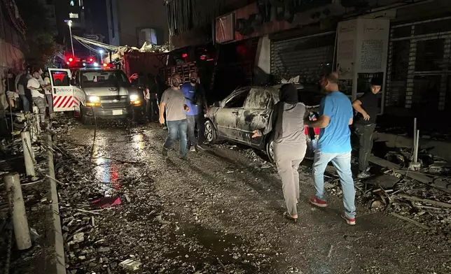 People walk near the building that was hit by an Israeli airstrike in the southern suburbs of Beirut, Lebanon, Tuesday, July 30, 2024. An Israeli airstrike hit Hezbollah's stronghold south of Beirut Tuesday evening causing damage, a Hezbollah official and the group's TV station said. (AP Photo/Hussein Malla)