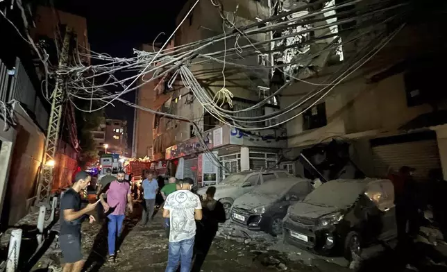 People gather near a destroyed building that was hit by an Israeli airstrike in the southern suburbs of Beirut, Lebanon, Tuesday, July 30, 2024. An Israeli airstrike hit Hezbollah's stronghold south of Beirut Tuesday evening causing damage, a Hezbollah official and the group's TV station said. (AP Photo/Hussein Malla)