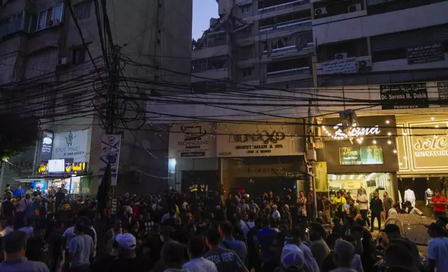 People gather near a destroyed building that was hit by an Israeli airstrike in the southern suburbs of Beirut, Lebanon, Tuesday, July 30, 2024. An Israeli airstrike hit Hezbollah's stronghold south of Beirut Tuesday evening causing damage, a Hezbollah official and the group's TV station said. (AP Photo/Hassan Ammar)