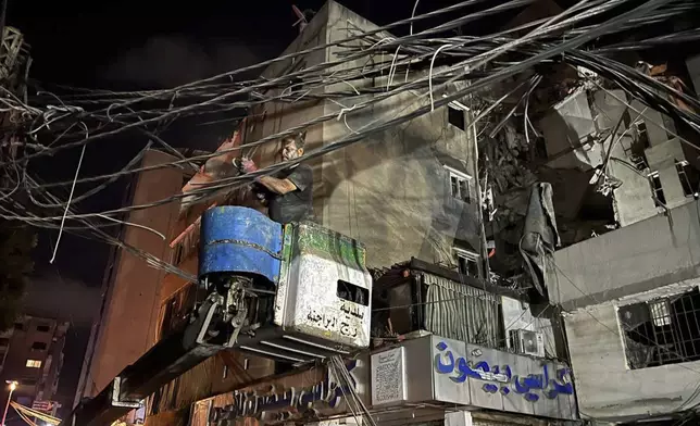 A man removes power cables near a destroyed building that was hit by an Israeli airstrike in the southern suburbs of Beirut, Lebanon, Tuesday, July 30, 2024. An Israeli airstrike hit Hezbollah's stronghold south of Beirut Tuesday evening causing damage, a Hezbollah official and the group's TV station said. (AP Photo/Hussein Malla)