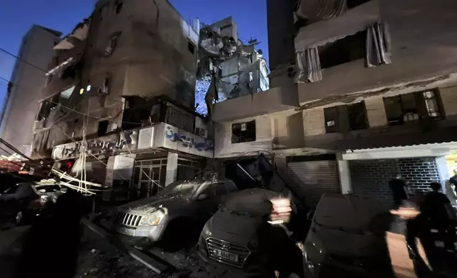 People inspect damaged cars in the southern suburbs of Beirut, Lebanon, Tuesday, July 30, 2024. An Israeli airstrike hit Hezbollah's stronghold south of Beirut Tuesday evening causing damage, a Hezbollah official and the group's TV station said. (AP Photo/Hussein Malla)