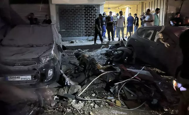 People inspect damaged cars in the southern suburbs of Beirut, Lebanon, Tuesday, July 30, 2024. An Israeli airstrike hit Hezbollah's stronghold south of Beirut Tuesday evening causing damage, a Hezbollah official and the group's TV station said. (AP Photo/Hussein Malla)