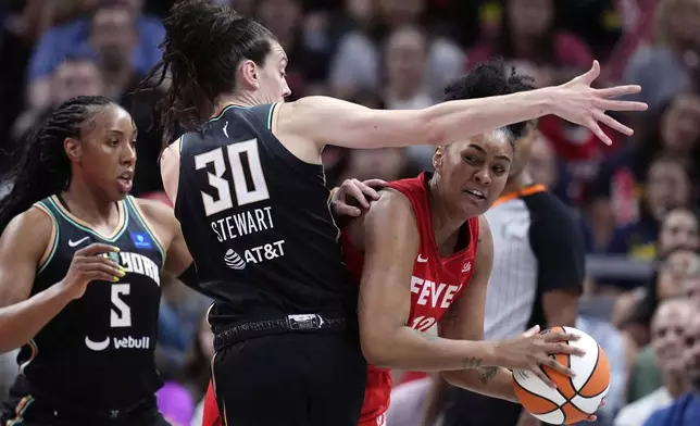 Indiana Fever's Damiris Dantas (12) makes a pass against New York Liberty's Breanna Stewart (30) and Kayla Thornton (5) during the first half of a WNBA basketball game, Saturday, July 6, 2024, in Indianapolis. (AP Photo/Darron Cummings)