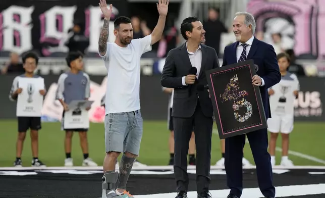 Inter Miami forward Lionel Messi, left, waves to the crowd as he is awarded for his 45 career trophies before an MLS soccer match against the Chicago Fire, Saturday, July 20, 2024, in Fort Lauderdale, Fla. At right is Inter Miami managing owner Jorge Mas. (AP Photo/Lynne Sladky)