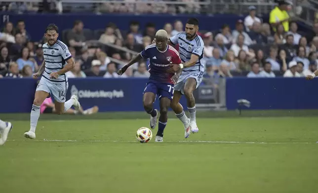 FC Dallas midfielder Bernard Kamungo (77) is chased by Sporting Kansas City defender Robert Castellanos (19) during the first half of an MLS soccer match Sunday, July 7, 2024, in Kansas City, Kan. (AP Photo/Charlie Riedel)