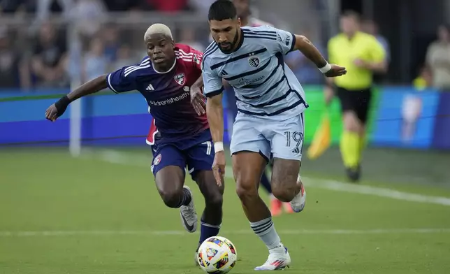 FC Dallas midfielder Bernard Kamungo, left, and Sporting Kansas City defender Robert Castellanos (19) chase the ball during the first half of an MLS soccer match Sunday, July 7, 2024, in Kansas City, Kan. (AP Photo/Charlie Riedel)