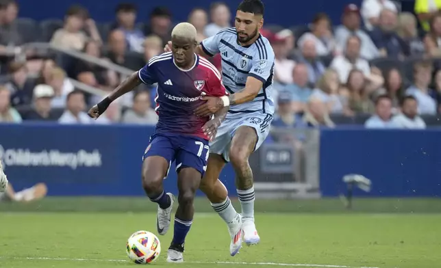 FC Dallas midfielder Bernard Kamungo (77) is chased by Sporting Kansas City defender Robert Castellanos (19) during the first half of an MLS soccer match Sunday, July 7, 2024, in Kansas City, Kan. (AP Photo/Charlie Riedel)