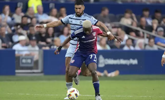 FC Dallas midfielder Bernard Kamungo (77) is chased by Sporting Kansas City defender Robert Castellanos (19) during the first half of an MLS soccer match Sunday, July 7, 2024, in Kansas City, Kan. (AP Photo/Charlie Riedel)