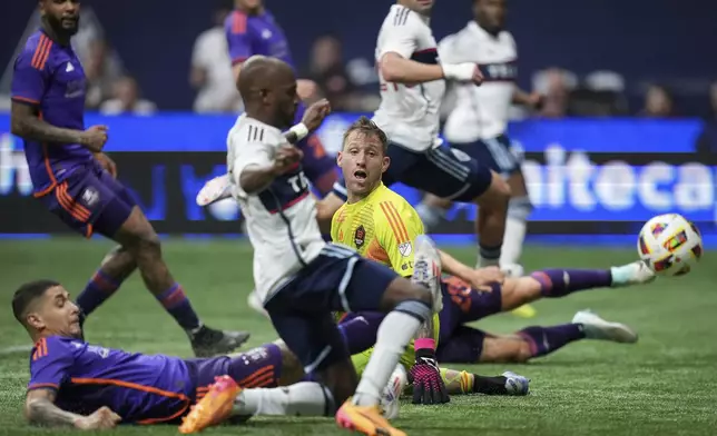 Houston Dynamo goalkeeper Steve Clark, back center, watches as Vancouver Whitecaps' Fafa Picault, front, scores a goal during the second half of an MLS soccer match in Vancouver, British Columbia, Saturday, July 20, 2024. (Darryl Dyck/The Canadian Press via AP)