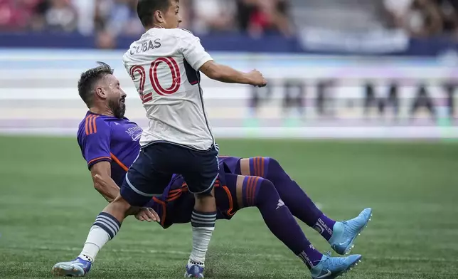 Vancouver Whitecaps' Andres Cubas (20) and Houston Dynamo's Hector Herrera, left, collide during the first half of an MLS soccer match in Vancouver, British Columbia, Saturday, July 20, 2024. (Darryl Dyck/The Canadian Press via AP)