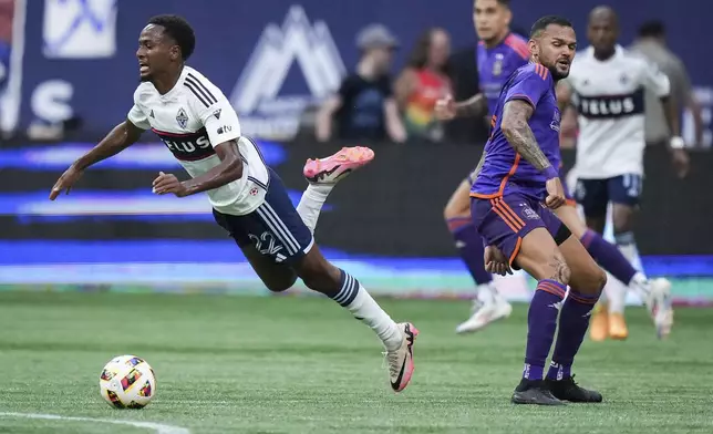 Vancouver Whitecaps' Ali Ahmed, left, is upended by Houston Dynamo's Artur, front right, during the first half of an MLS soccer match in Vancouver, British Columbia, Saturday, July 20, 2024. (Darryl Dyck/The Canadian Press via AP)